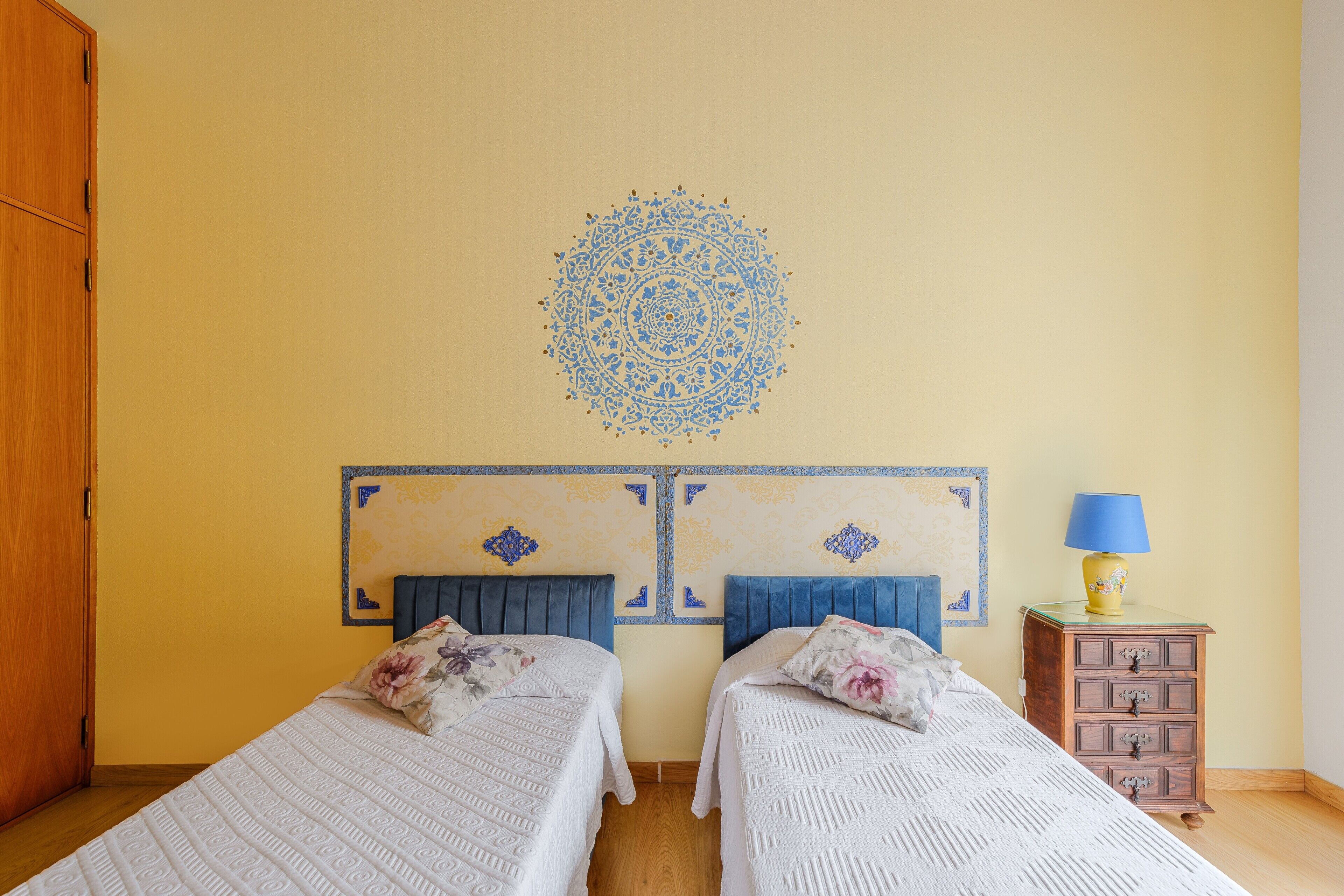 A bedroom with two beds, a dresser, and a decorative wall piece.