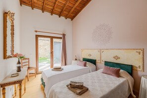 Un dormitorio con dos camas, un escritorio de madera, una silla y un ventanal grande.