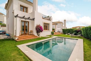 A modern two-story house with a swimming pool, a balcony, and a well-maintained garden.