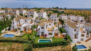 Zona residencial con edificios blancos, una piscina y vistas al mar.