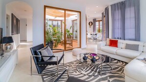 Una sala moderna con un sofá, una silla, una mesa de centro y un comedor al fondo.