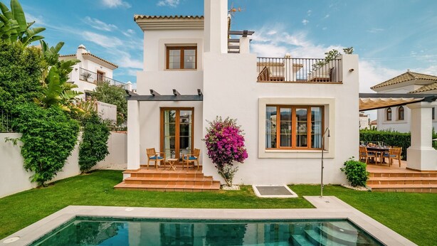Una casa moderna de dos pisos con piscina, balcón y jardín cuidado.