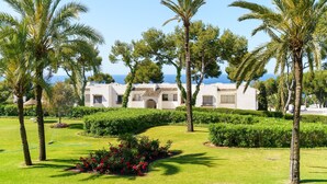 Un resort con palmeras, césped impecable y un edificio de estilo arquitectónico mediterráneo.