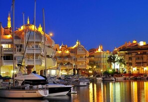 A marina with boats docked, a building with a dome, and a clear sky.