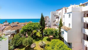 Un quartier résidentiel situé sur la côte, avec des bâtiments blancs, un ciel bleu dégagé et une vue sur la mer.