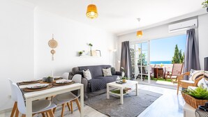Un salon moderne comprenant un canapé, une table à manger et des chaises, une table basse et une vue sur l’extérieur.