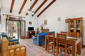 A living room with a sofa, wooden chairs, a TV, and a cabinet.