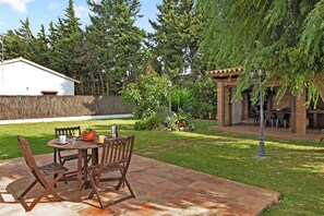 A patio with a table and chairs, surrounded by a well-maintained lawn and trees.