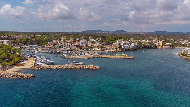 Une ville côtière dotée d’un port de plaisance, de bâtiments et, en arrière-plan, de montagnes.