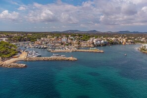 A coastal town with a marina, buildings, and mountains in the background.