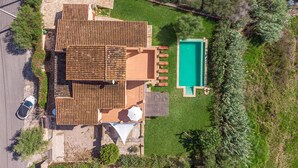 Une vue aérienne d’une maison avec un toit en tuiles, une piscine et une voiture garée à l’extérieur.