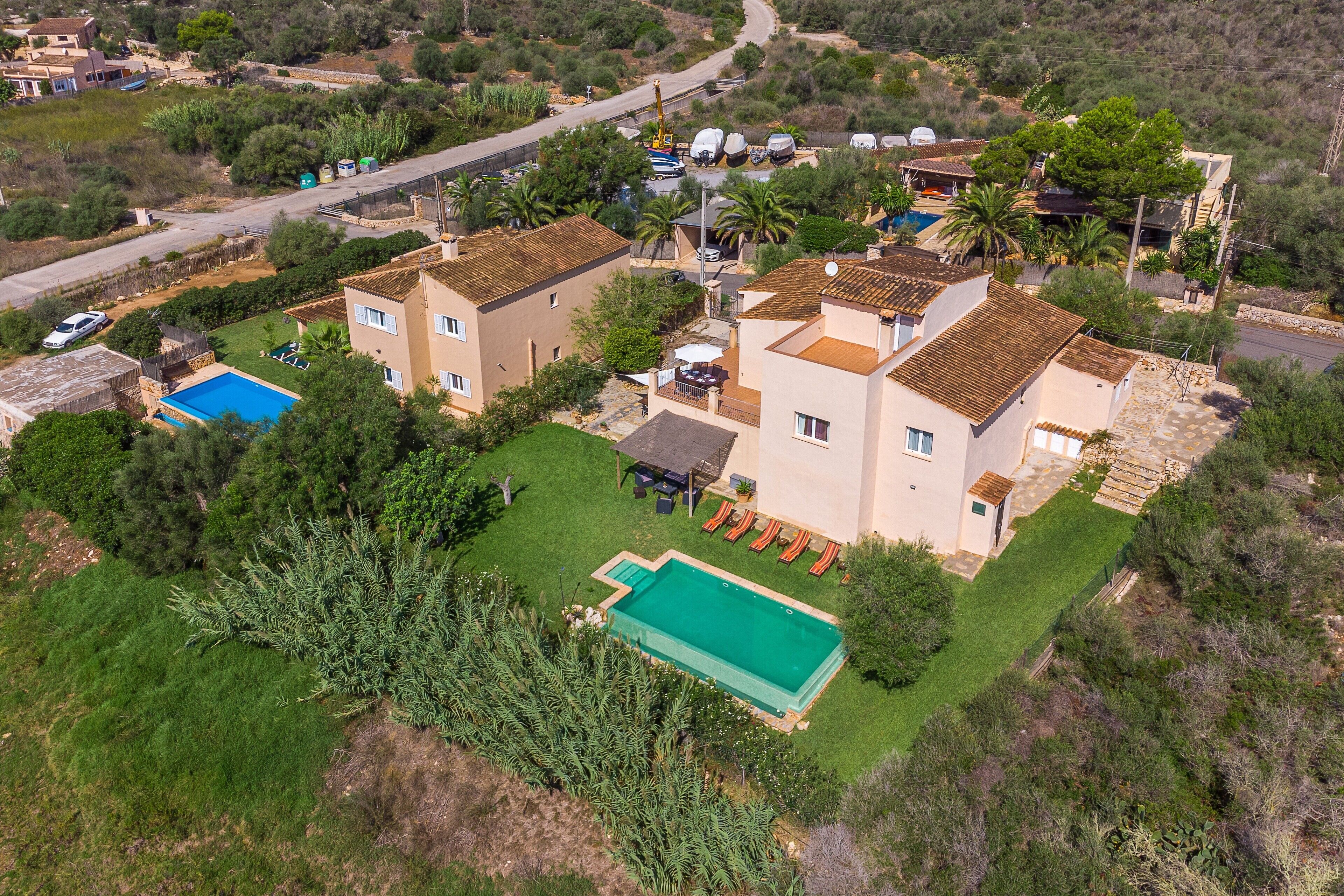 A residential area with multiple houses, a swimming pool, and a road.