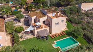 Une maison à deux étages avec une piscine, une terrasse dotée de mobilier d’extérieur et un jardin.