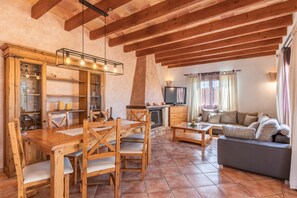A cozy living area with a wooden dining table, chairs, a sofa, and a fireplace.