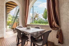 Un patio con una mesa y sillas, vista a la vegetación y un puente, y una decoración de piedra sobre la mesa.