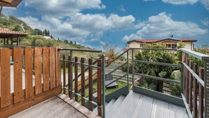 Ein Holzzaun, Metalltreppen und der Blick auf ein Haus mit rotem Dach.