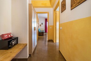 Un couloir avec un banc, un coffre-fort et une porte donnant sur une autre pièce.