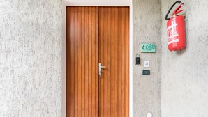 A wooden door with a metal handle, a fire extinguisher, and a small green sign on the wall.