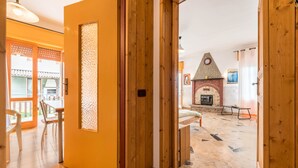 A wooden door leading to a room with a tiled floor, a fireplace, and a balcony with a view.