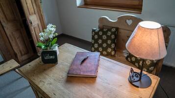 Una mesa de madera con un libro, un cartel que dice 'Welcome', una lámpara y un cojín floral.