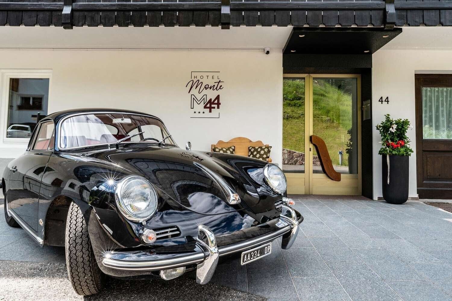 En klassisk, sort cabriolet holder foran et hotel ved navn 'Monte M4'.