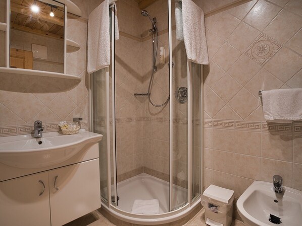 Une salle de bain avec une douche à parois de verre, un lavabo, un bidet et un miroir.
