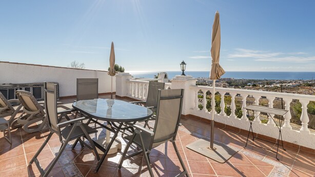 Una terraza con mesa y sillas, una lámpara y vista al mar.