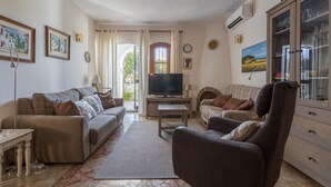 Una sala de estar con sofá, sillón, televisión y aparador.