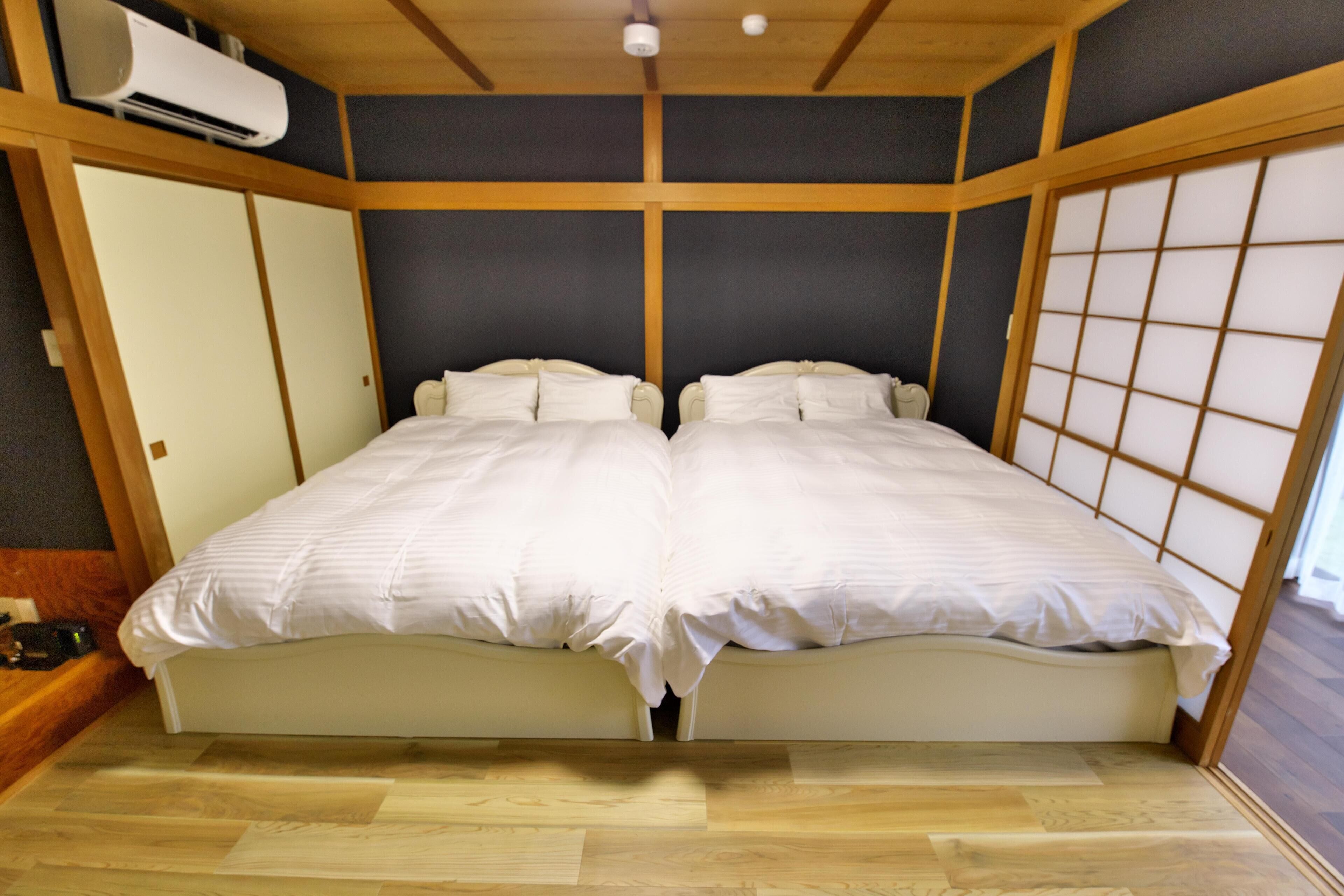 Een kamer met een tweepersoonsbed, houten vloeren en een traditionele Japanse schuifdeur.