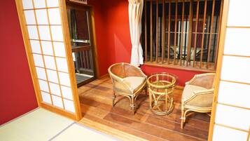 A room with a sliding door, two wicker chairs, a small glass table, and a window with bars.