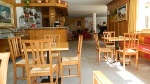 A wooden interior with a kitchen area, dining tables, and chairs. - Monterosa Residence Hotel (Macugnaga)
