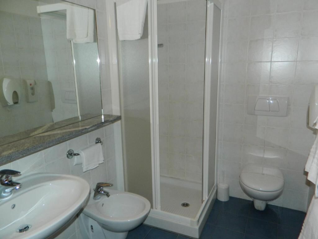 A bathroom with a shower, two sinks, a toilet, and a mirror.