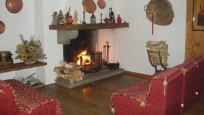 A cozy living room with a fireplace, wooden furniture, and decorative items. - Monterosa Residence Hotel (Macugnaga)