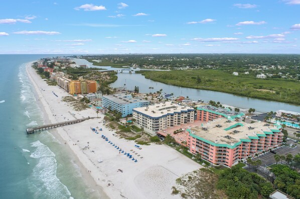 A coastal hotel with multiple buildings, a beach, and a pier.