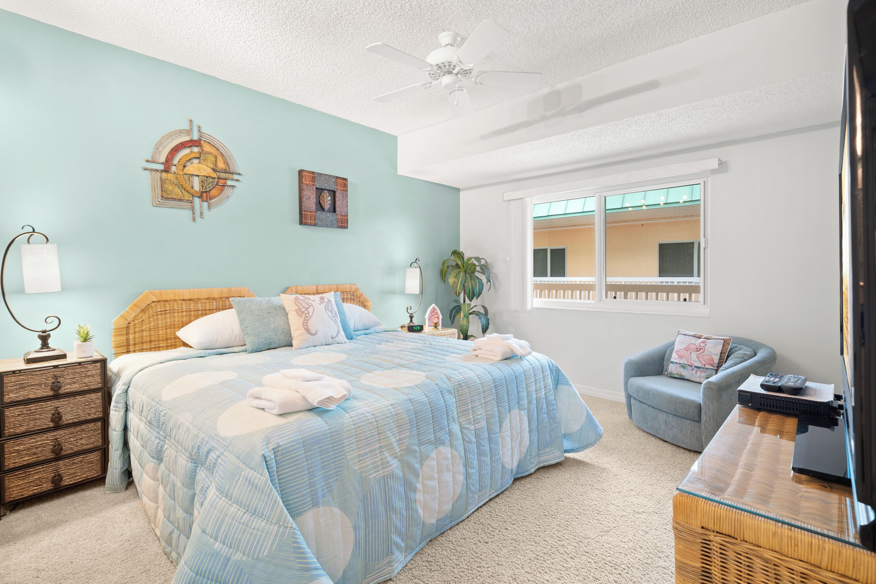 A bedroom with a bed, a chair, a nightstand, a lamp, and a window.