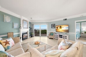 A spacious living room with a fireplace, comfortable seating, and a large TV.