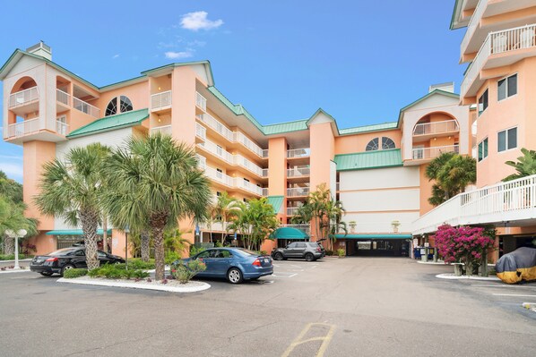Un hôtel à plusieurs étages doté de balcons, d’un parking et de palmiers.