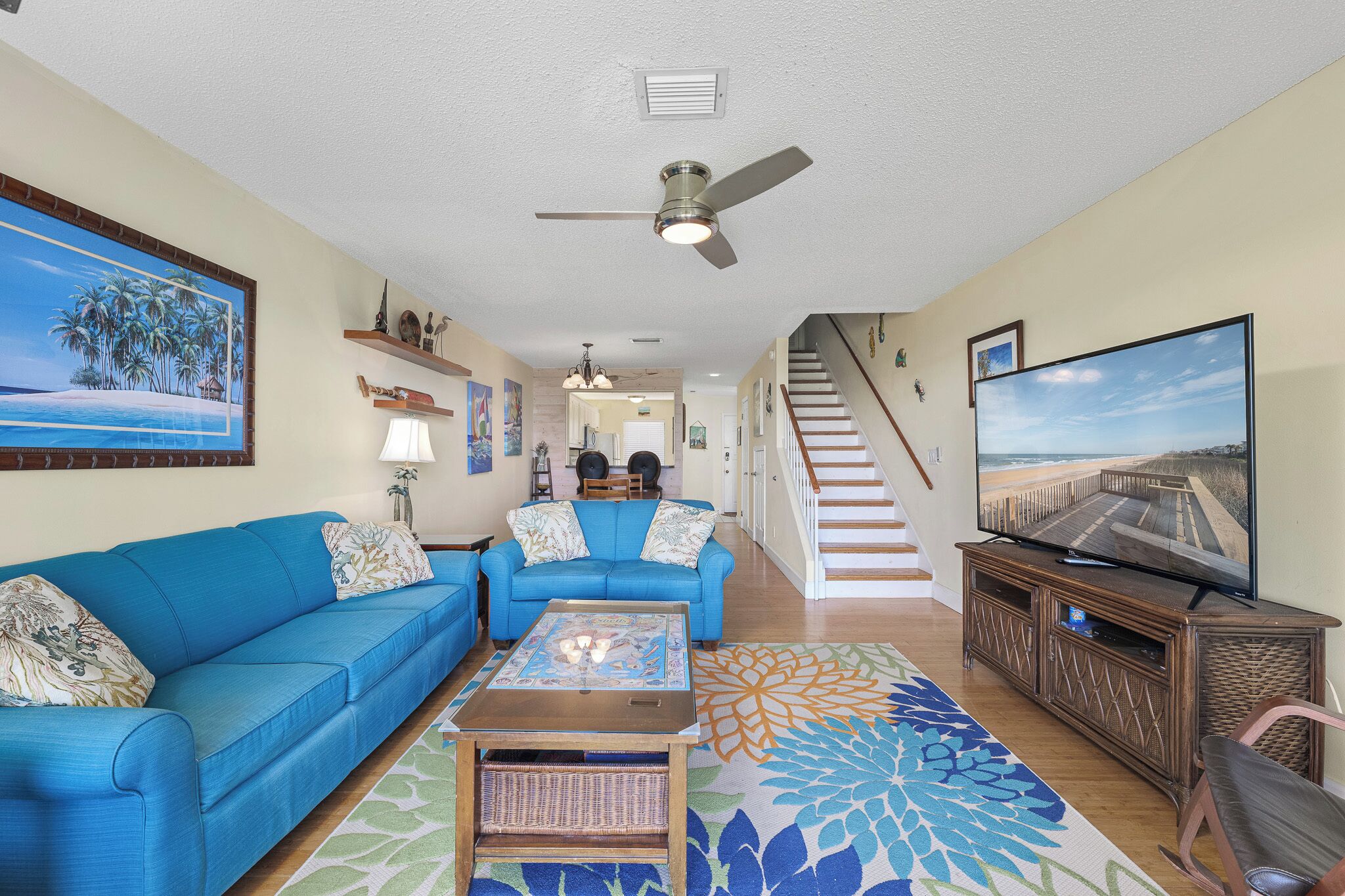 A living room with a blue sofa, a coffee table, a TV, and a staircase leading to another level.