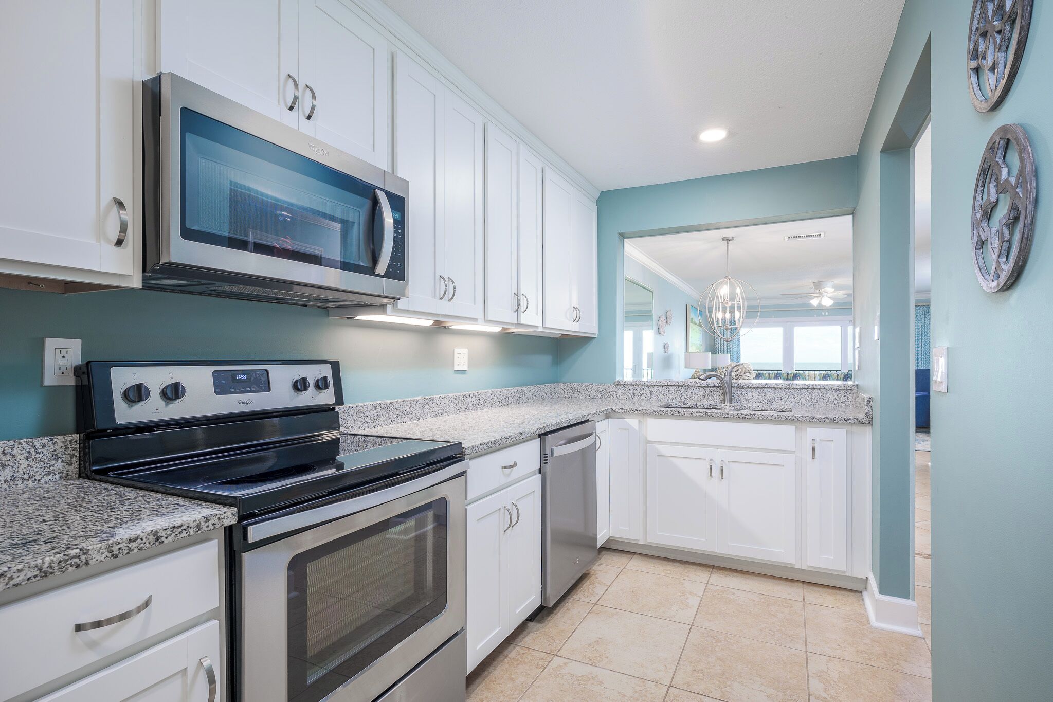 A modern kitchen with white cabinets, stainless steel appliances, and a granite countertop.