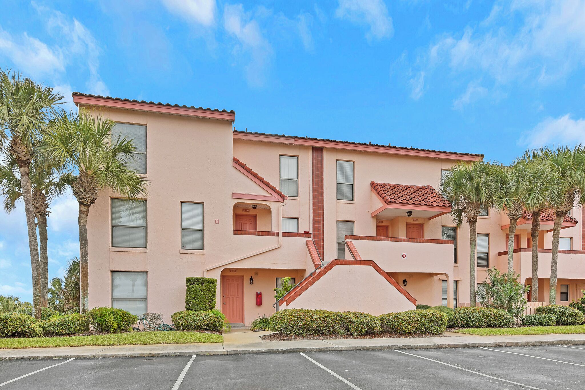 A multi-story hotel with a flat roof, balconies, and a parking lot.