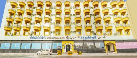 A hotel with multiple balconies, a prominent OYO sign, and a large entrance with a decorative arch.