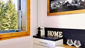 A modern kitchen with a view of a mountain, a framed photo on the wall, and a 'HOME' sign on the counter. - Cozy Retreat in Courchevel: 4 People, Ski-in/Ski-out, Wifi (Courchevel 1550)