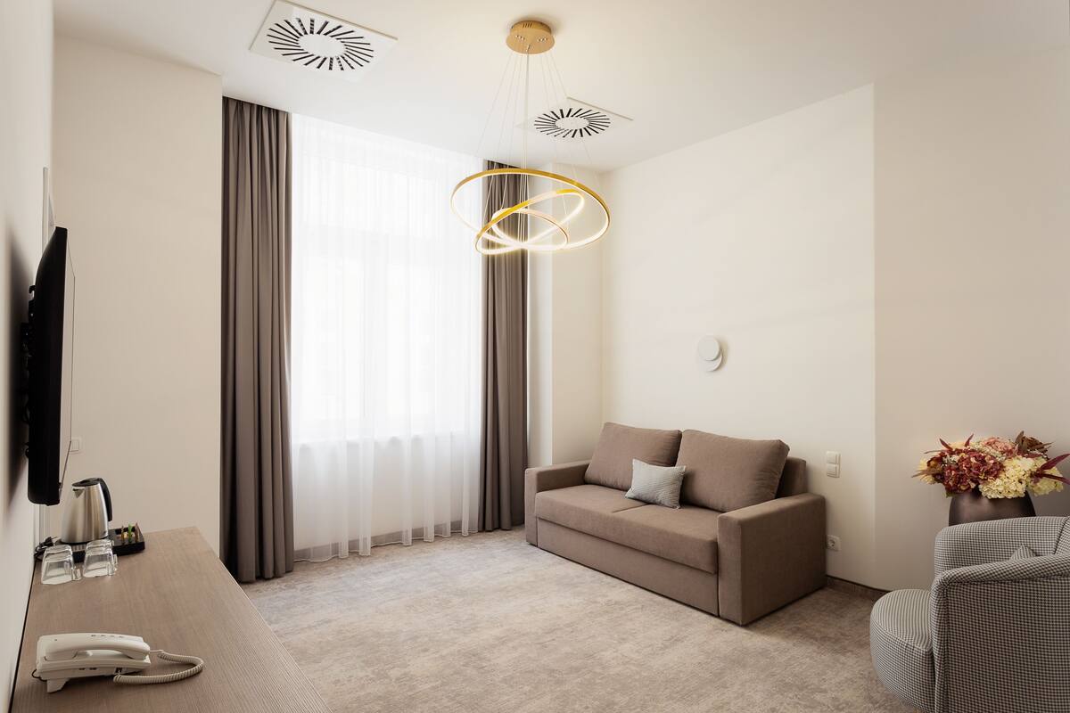 A modern hotel room with a sofa, a coffee table, a telephone, and a decorative vase.