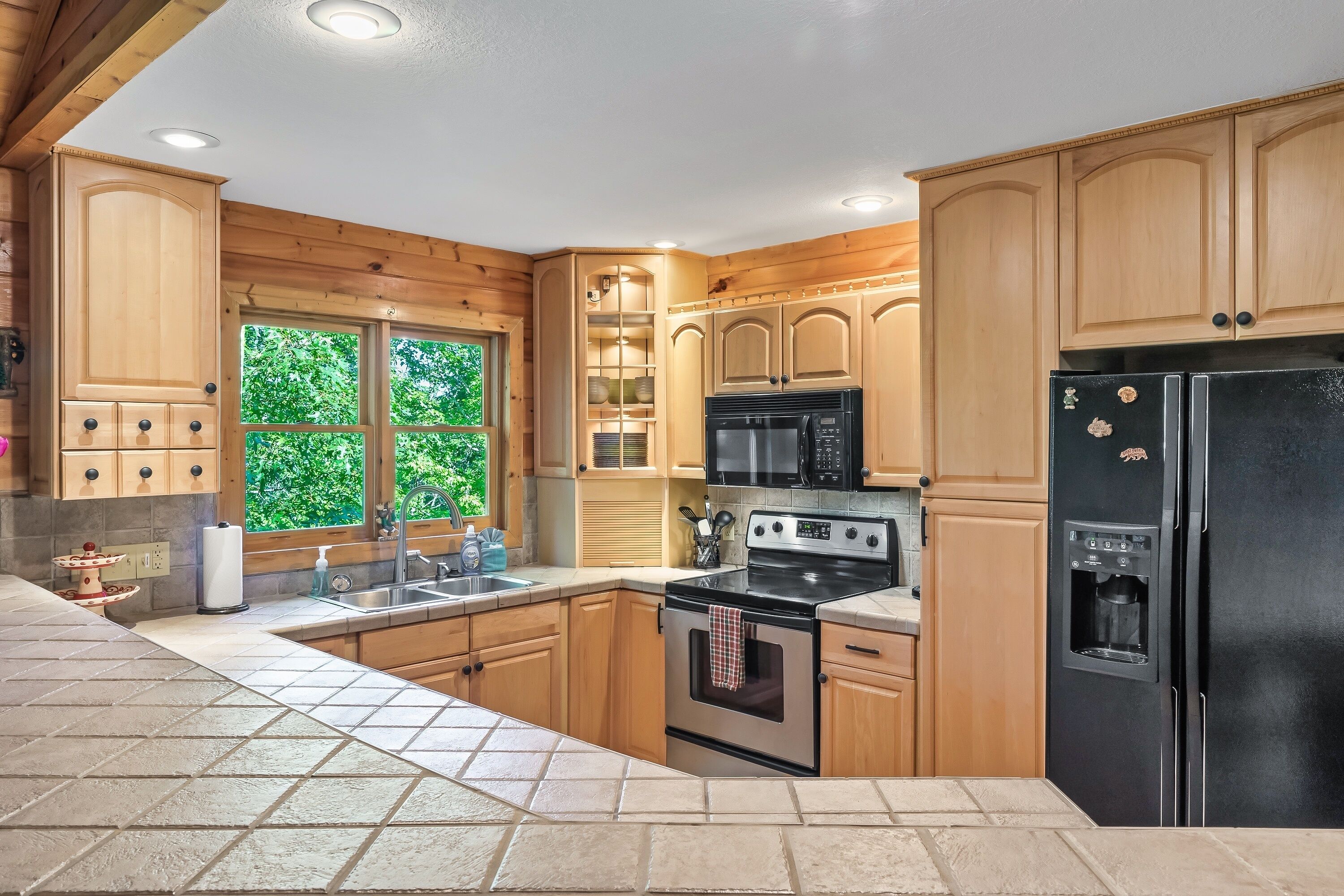Una cocina con armarios de madera, estufa, microondas y refrigerador.