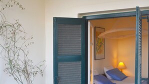 Een kamer met een bed, een stoel en een grote vaas met takken.