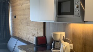 A compact kitchenette with a microwave, coffee maker, and toaster.