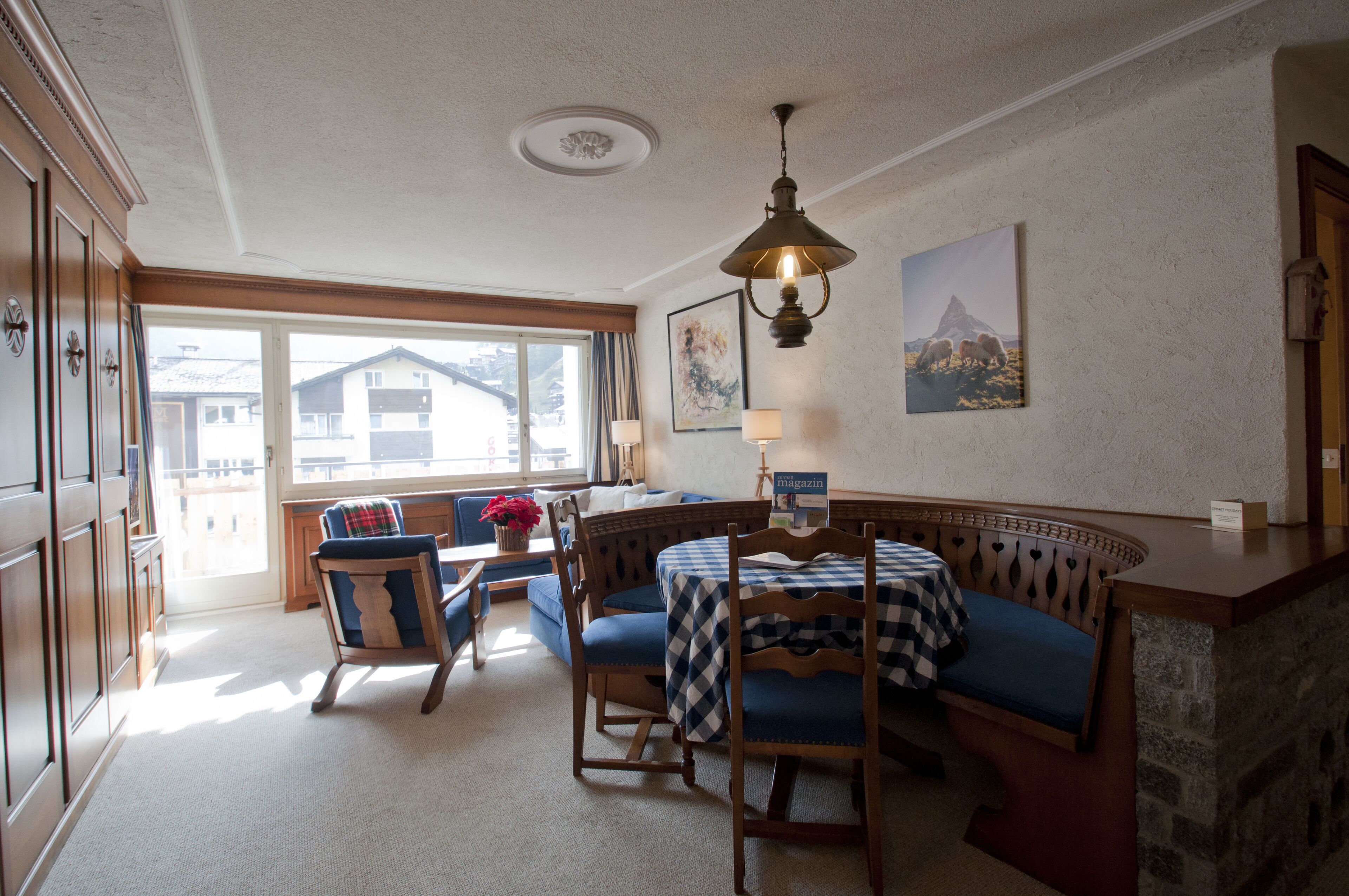 A cozy dining area with a wooden bench, a table with a checkered tablecloth, and a hanging light fixture.