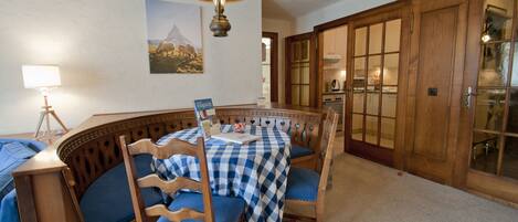 A dining area with a checkered tablecloth, wooden chairs, and a pendant light.