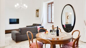Ein modernes Wohnzimmer mit einem runden Holzesstisch, einem grauen Sofa, einem Flachbildfernseher und einem großen Spiegel.