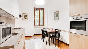 Eine kompakte Küche mit modernen Geräten, ein Essbereich mit Tisch und Stühlen sowie ein Fenster mit Blick auf Grünflächen.